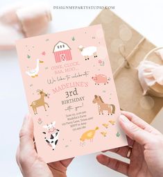 a person holding up a pink birthday card with farm animals and barn designs on it