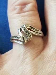 Sterling silver swirl ring with diamonds. The ring is a US size 6 3/4. It contains 12 diamonds at 0.005 cts for a total of 0.06 cts. The diamond has swirled middle and the diamonds are mounted to the right and left and to one part of the swirl. This will make a lovely gift for a special person as a promise, anniversary or friendship ring. Silver Bypass Ring With Diamond Accents For Anniversary, Silver Round Bypass Ring For Formal Occasions, Silver Bypass Ring With Diamond Accents For Formal Occasions, Formal Silver Round Bypass Ring, Formal Silver Bypass Ring With Diamond Accents, Silver Bypass Ring For Anniversary, Fine Jewelry Silver Bypass Ring With Diamond Accents, Silver Bypass Ring With Diamond Accents, Silver Bypass Ring With Diamond Accents For Gift