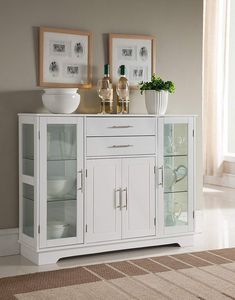 white kitchen cabinets with glass doors and cupboards in the middle of a living room