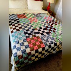 a bed with a quilt on top of it in a bedroom next to a lamp