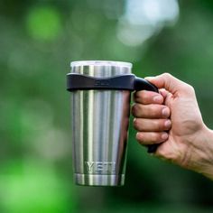 a person holding a coffee cup in their left hand with the lid up and one hand on the other