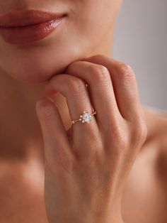 a close up of a person wearing a gold ring with a diamond on the middle