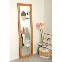 a large mirror sitting on top of a wooden floor next to a vase with flowers