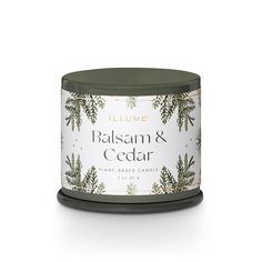 a candle that reads balsam and cedar with pine branches on the front, in a tin