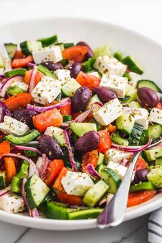 a white bowl filled with cucumber, red onion and feta cheese salad