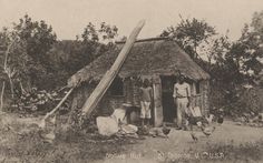 an old black and white photo of two men standing in front of a hut