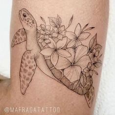 a turtle and flowers tattoo on the side of a woman's leg, with her arm