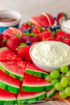 watermelon slices, grapes and strawberries are arranged on a platter with dip