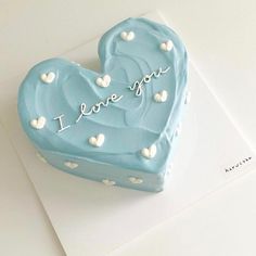 a blue heart shaped cake with i love you written on the top and white hearts around it