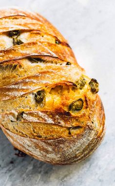 a loaf of bread sitting on top of a white countertop covered in olives