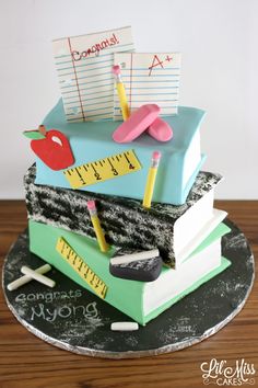 there is a cake made to look like books with rulers and apple on top,