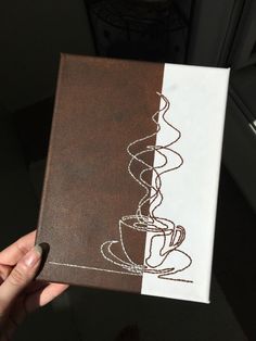 a person holding up a book with a coffee cup drawn on the front and side