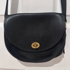 Exceptionally Beautiful And Pristine, This Black Coach Pocket Purse Is A Rare Discovery In Impeccable Condition. It Has Seen Minimal Use, If Any, As The Leather Remains Gorgeous And Unblemished, Still Retaining Its Original Stiffness, Reminiscent Of A Brand-New Purse. Remarkably Free From Scratches, This Petite Purse Boasts A Surprising Amount Of Functionality With 2-Pockets. The Exterior Features A Sizable Pocket Spanning The Length Of The Purse Beneath The Front Flap, As Well As Another Substantial Pocket Inside. The Purse Comes Complete With Its Original Hangtag, Adding To Its Authenticity. The Hardware, Crafted From Solid Brass, Includes A Turn-Lock Closure And A Functional Clip-On Shou Classic Crossbody Satchel For Errands, Classic Satchel For Errands, Classic Saddle Bag With Adjustable Strap For Shopping, Classic Saddle Bag For Shopping, Classic Saddle Bag For Errands, Coach Satchel Shoulder Bag With Magnetic Closure, Coach Everyday Saddle Shoulder Bag, Coach Everyday Shoulder Saddle Bag, Coach Shoulder Bag With Magnetic Closure For Everyday