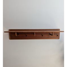 a wooden shelf with three hooks on it