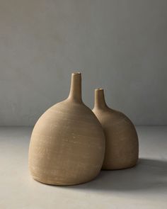 two clay vases sitting side by side on a white surface with no one around them