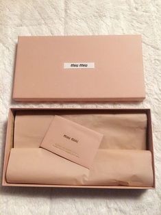 an open pink box with a tag on it sitting on top of a white blanket