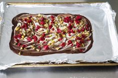 a chocolate cake with white and red toppings on top of aluminum baking sheet, ready to be baked