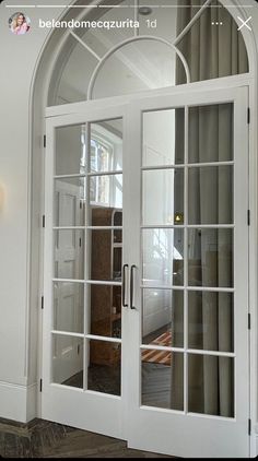 an arched glass door leading into a living room with white walls and wood flooring