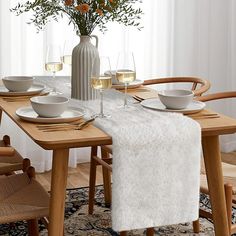 a dining room table with white dishes and wine glasses