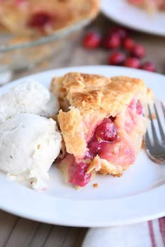 a piece of pie on a plate with ice cream and cranberries next to it