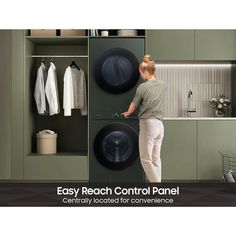 a woman standing in front of a washer next to a dryer and cabinets