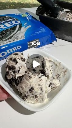 ice cream in a bowl being held up by someone's hand next to a bag of oreo cookies