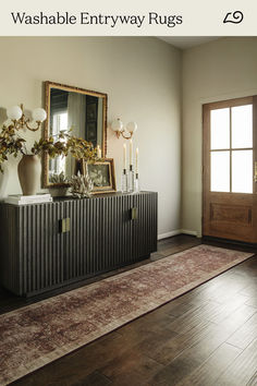 an entryway rug is on the floor next to a cabinet with candles and vases