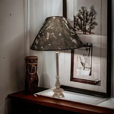 a lamp sitting on top of a wooden table next to a framed picture and vase