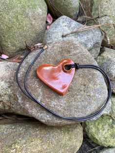 a red heart shaped pendant sitting on top of a rock