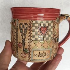 a hand holding a coffee mug with designs on it