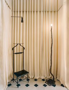 a black chair sitting in front of a window next to a tall metal object on a checkered floor