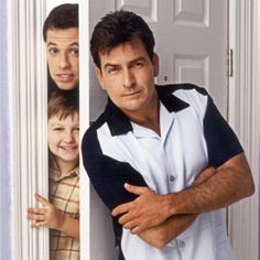 a man leaning against a door with his arms crossed and two children looking at him