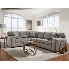 a living room with a sectional couch and coffee table in front of two large windows