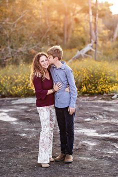 a young man and woman embracing each other while standing in front of yellow wildflowers