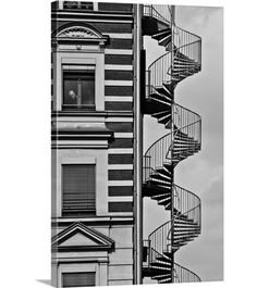 a black and white photo of a spiral staircase in front of a building with windows