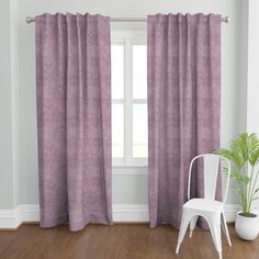 a white chair sitting in front of a window with purple polka dot curtains on it