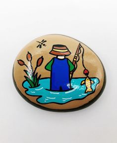 a man with a fishing pole and fish in the water painted on a wooden button