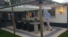 a man standing in front of a white house holding onto an awning over a table