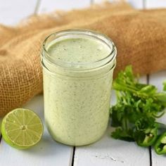 a green smoothie in a mason jar next to a lime and cilantro garnish