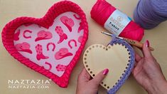 a person holding a heart shaped object next to yarn