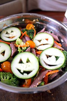 a bowl filled with vegetables and cut up jack - o'- lantern faces on them