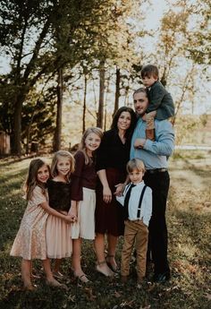 a family poses for a photo in the woods with their two children and one adult