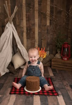 a baby is sitting on the floor with a cake in front of him and smiling at the camera