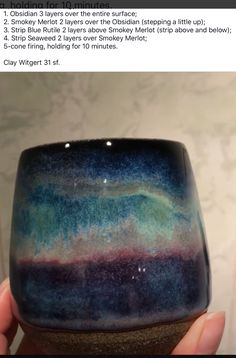 a hand holding up a cup that has been made to look like the sky