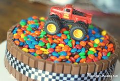 a birthday cake with a monster truck in the middle and lots of candy on top