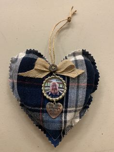 a heart shaped ornament hanging on a wall with a ribbon attached to it