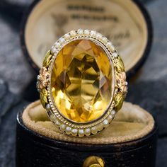 This antique ring features of both the Art Deco and Retro 1940s period. The central oval cut citrine is accented by an engraved border and two sections of seed pearls carefully set onto a wire. The shoulders of the ring are accented with openwork and two-tone floral designs. The ring is crafted in 14k white gold with yellow and rose gold accents, and is currently a size 6. Please note that one seed pearl seems to be missing, but it does not detract from the beauty or symmetric look of the ring. Rose Gold Accents, Antique Ring, Citrine Ring, Seed Pearl, Antique Rings, Floral Designs, Tri Color, Gold Accents, Oval Cut