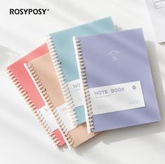 three notebooks sitting next to each other on top of a white table with a laptop