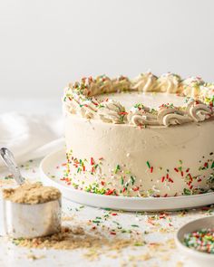 a cake with white frosting and sprinkles sitting on top of a table