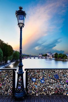 a lamp post covered in padlocks next to a river